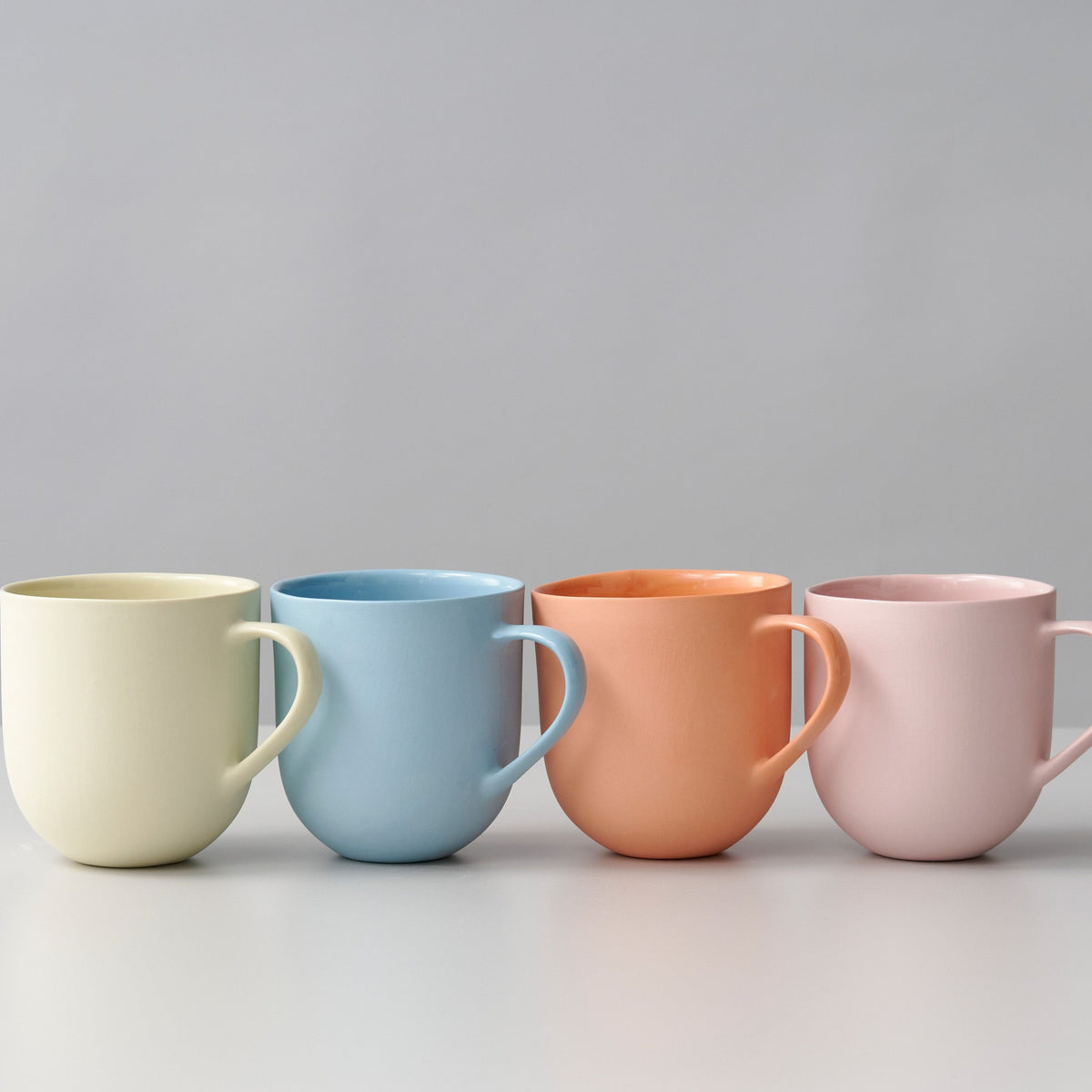 Handmade porcelain mug with flared shape, glazed handle, and smooth stone-like exterior, perfect for tea or coffee.