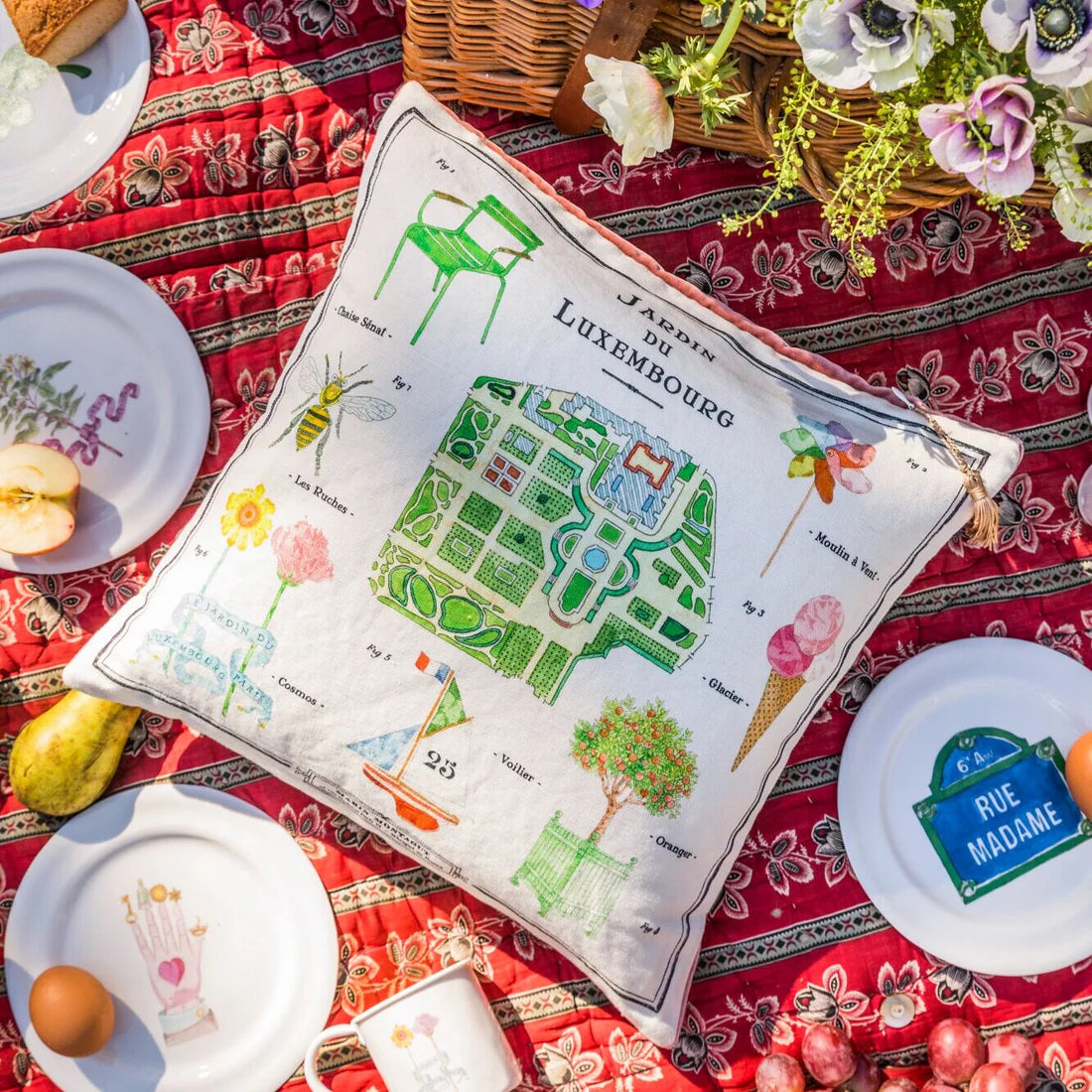 The French Cushion: Luxembourg Garden&nbsp;by Marin Montagut brings a whimsical touch to your home with its charming design. Featuring an illustration by Marin Montagut, this cushion adds a playful element to any space. Pink velvet back and tassle