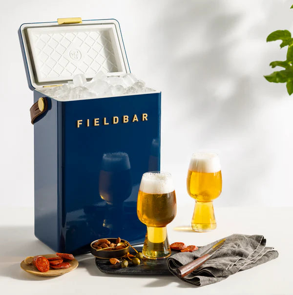 FIELDBAR Drinks Box hardcase cooler with leather handle and brass-coated hardware, showcasing its sleek design and Pantone 10C color, placed on an outdoor surface. Drinks Box / Sea Boat Blue