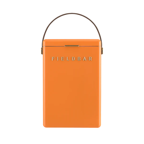 FIELDBAR Drinks Box hardcase cooler with leather handle and brass-coated hardware, showcasing its sleek design and Pantone 2025 color, placed on an outdoor surface. Drinks Box /Orchard Orange