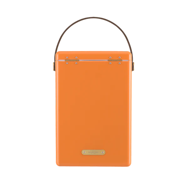 FIELDBAR Drinks Box hardcase cooler with leather handle and brass-coated hardware, showcasing its sleek design and Pantone 2025 color, placed on an outdoor surface. Drinks Box /Orchard Orange