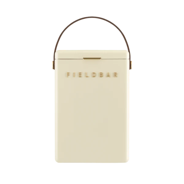 FIELDBAR Drinks Box hardcase cooler with leather handle and brass-coated hardware, showcasing its sleek design and Pantone 10C color, placed on an outdoor surface. Drinks Box / Safari White