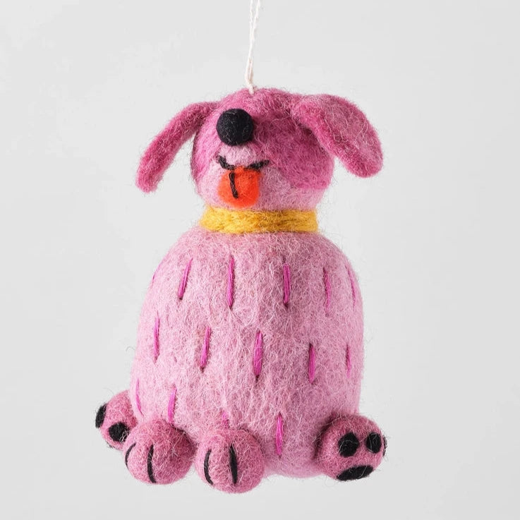 tina a pink felt dog ornament. Cartoon like she is sticking out his tongue and sitting up right. Eyes are closed and have a black button nose 